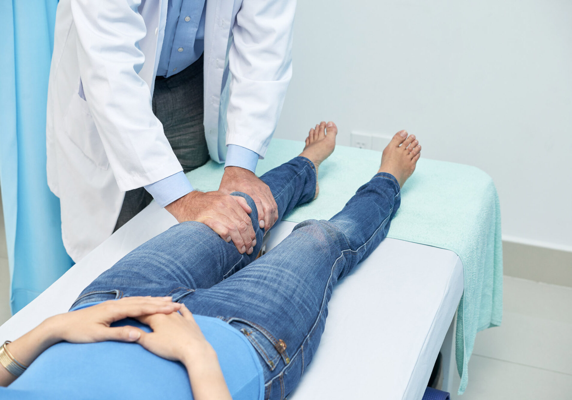 Cropped image of chiropractor checking knee of young patient